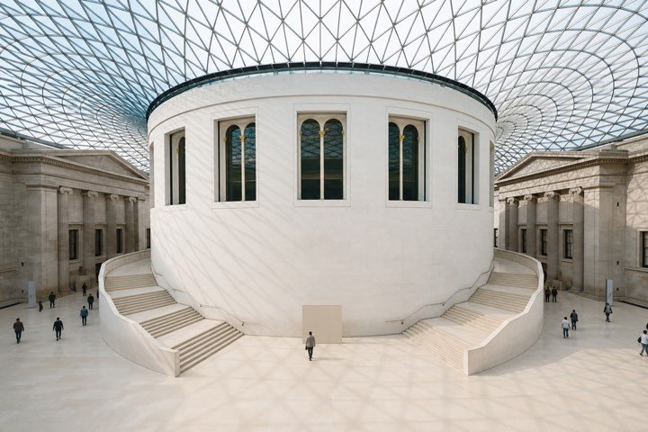 A light-filled London museum interior beneath a glass roof