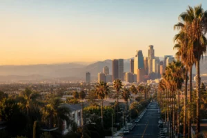 Los Angeles skyline, palm-lined street and distant hills in warm evening light