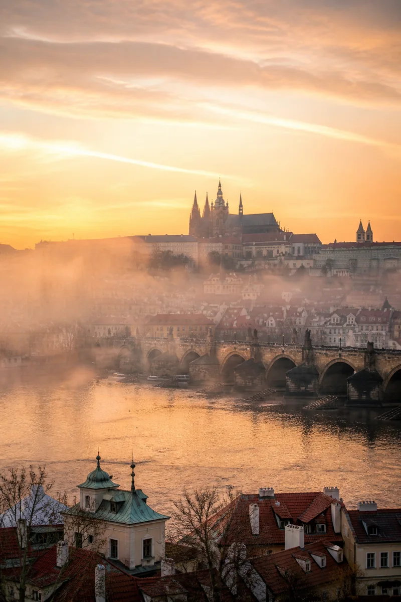 Prague Old Town rooftops, church spires and Charles Bridge in soft morning light